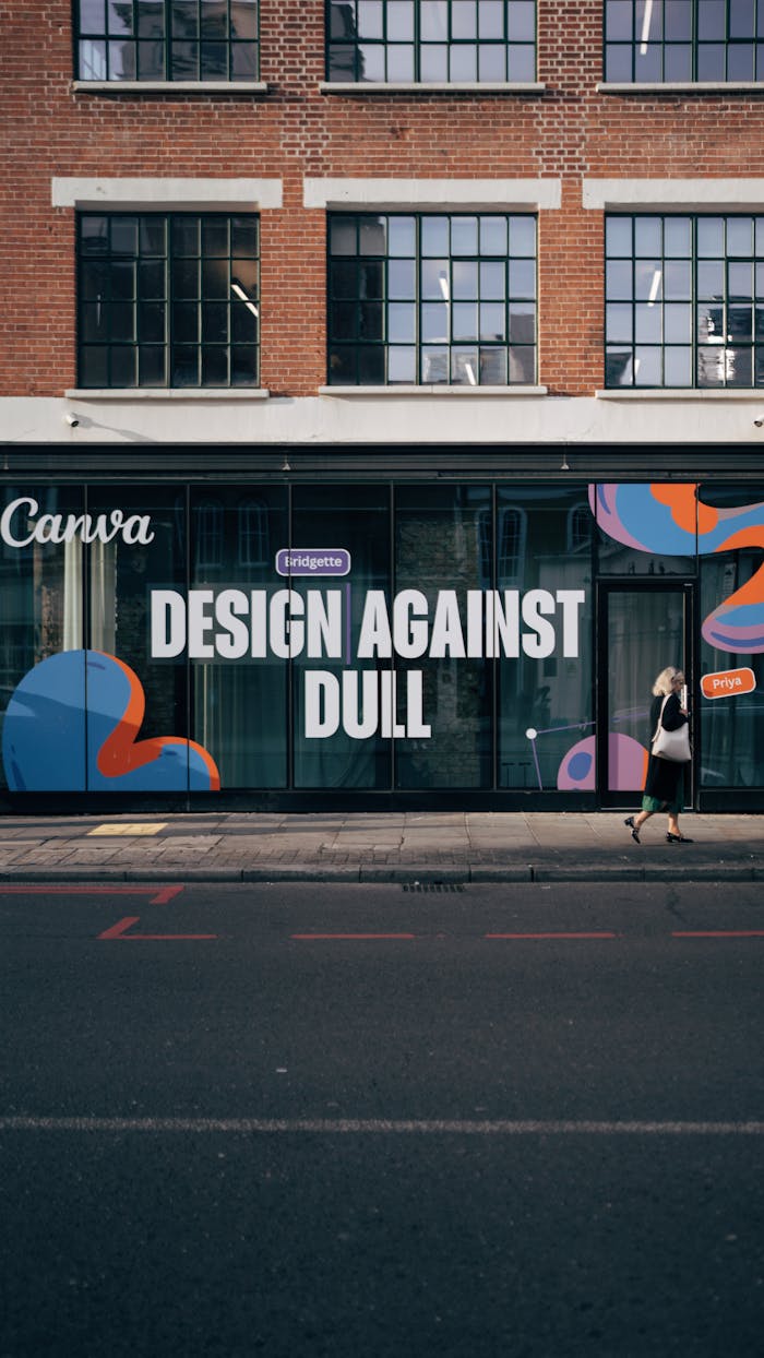 Street mural with Design Against Dull slogan on a modern urban building facade.